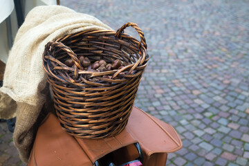 Brown wicker basket with two handles full of chestnuts put on bike rack for sale. Agricultural...