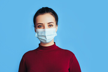 Woman in protective medical mask in front of a blue background. Health protection. Preventing disease during a pandemic