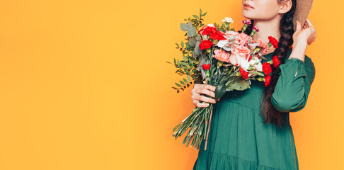 Woman holding a large bouquet of flowers in a green dress on a yellow background