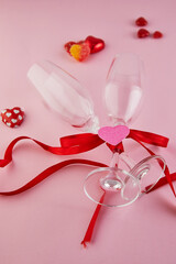 Valentine's day greeting card with glasses of champagne and candy hearts on pink background. Top view with a place for your greetings.