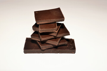 Dark chocolate stacked pieces on top of each other on white background space for text content