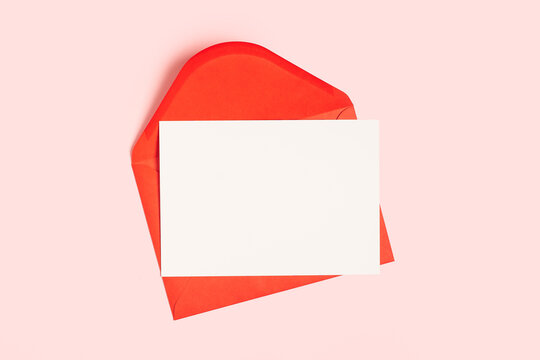 Red Paper Envelope With Blank White Note Mockup Inside On Pink Pastel Background. Flat Lay, Top View. Romantic Love Letter For Valentine's Day Concept.