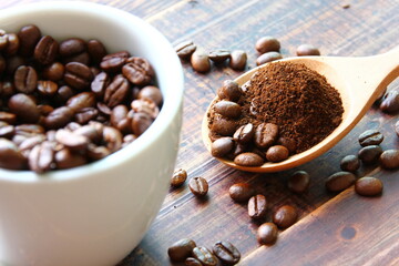 roasted coffee beans mix ground coffee on wooden spoon , roasted coffee beans on retro wood floor