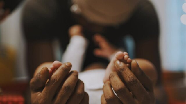 Close up, baby feet. Father and son bonding. African american man playing with little feet of his baby. High quality 4k footage