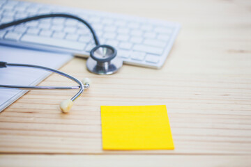 stethoscope  over computer keyboard on with yellow note paper a doctor desk at hospital