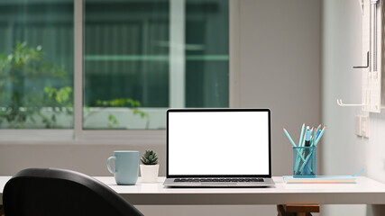 Mock up laptop computer with blank screen, coffee cup and stationery on designer workspace.