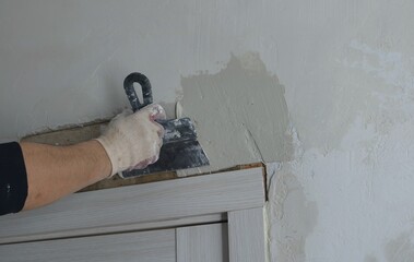 leveling the wall after installing the door frame, applying plaster with a medium trowel, elastic...