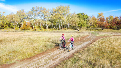 Fototapeta na wymiar Family on bikes autumn cycling outdoors, active mother and kid on bicycles, aerial view of happy family with child in fall park from above, sport and fitness concept 