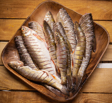 Flat lay fresh fish chub on a wooden squared brown plate on the wooden background