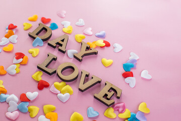 love day in different colored hearts on a pink background. Valentines day.