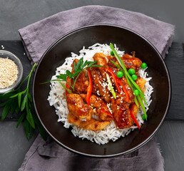 Chicken baked in sauce served with rice and vegetables on gray background.