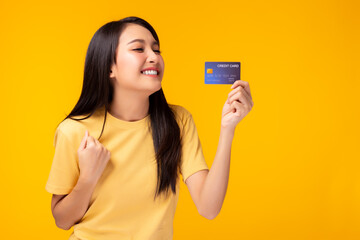 Happy young asian woman showing plastic credit card and looking at credit card with happy Standing over yellow background Customer girl get satisfied of credit card service with smile on face