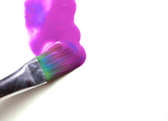 a wide brush paints in magenta on a white sheet of paper. close-up.