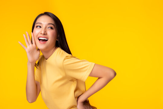 Surprised happy beauty asian woman looking copy space in excitement Expressive facial expressions Presenting some product. Beautiful girl act like a telling secret Isolated on yellow background