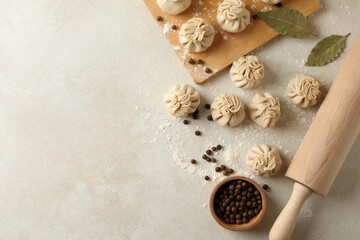 Concept of cooking with raw khinkali and spices on white textured background
