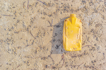 Empty Yellow plastic bottle single-used on sandy, Problem of garbage affects the marine ecosystem...