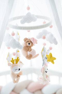 A crib and a toy above it. A delicate toy hangs over the children's bed. High quality photo.