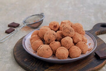 Homemade chocolate candy truffles on a dessert plate on a gray concrete background. Truffle candy recipes. Chocolate candies.