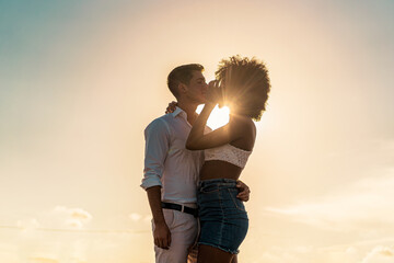 Couple of mixed race young people in live hugging and kissing outdoors