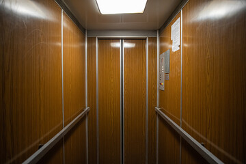 Interior inside a closed clean old Soviet elevator car lined with wood.