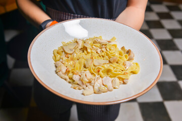 Waiter serving pasta bolognese in restaurant or diner. Eating out concept.