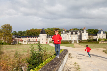 Two boys, happily playing after the rain on the driveway of French Gizeux castle