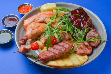 Assorted delicious grilled meat with vegetables over the lavash bread on a plate with different kinds of sauce.