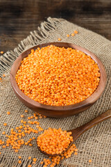 Red lentils in a wooden bowl on a brown wooden table