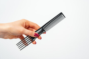Female hand holding hair comb against white background