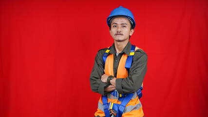 Asian worker man wearing uniform, helmet, safety harness isolated red background
