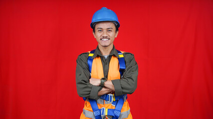 Asian worker man wearing uniform, helmet, safety harness isolated red background