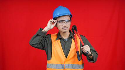 asian construction worker man wearing uniform, helmet, with cutter isolated red backgroubd