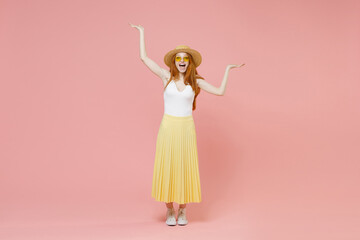 Obraz na płótnie Canvas Full length body young happy excited redhead woman in straw hat glasses summer clothes maxi skirt do winner gesture raised hands fool around look camera isolated on pink background studio portrait.