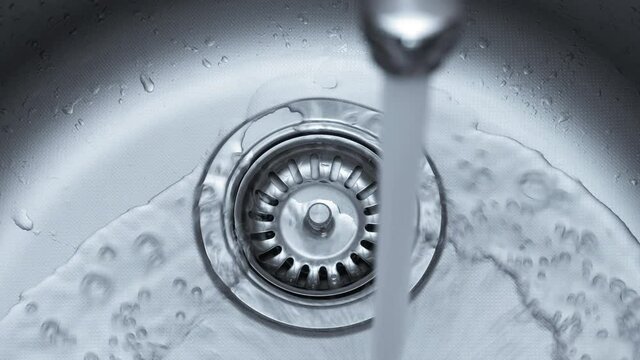 Streaming water in sink. Water stream going down the drain.