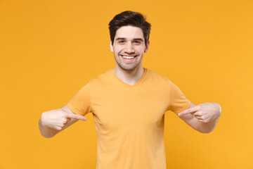 Young smiling unshaved caucasian man 20s in casual blank print design t-shirt point index two fingers on himself workspace copy space area look camera isolated on yellow background studio portrait.
