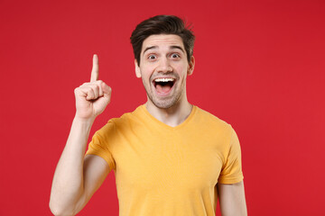 Young unshaved caucasian smiling student man 20s in casual basic yellow t-shirt holding index...