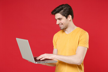 Young smiling unshaved caucasian student man 20s in casual basic yellow t-shirt using laptop pc...