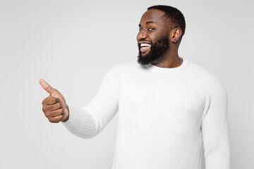 Smiling cheerful funny handsome attractive young african american man 20s wearing casual basic sweater standing showing thumb up looking camera isolated on white color wall background studio portrait.
