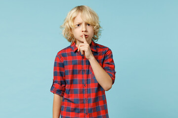 Secret little curly kid boy 10s years old in red checkered shirt say hush be quiet with finger on...