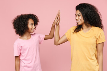 Funny african american young woman and little kid girl sisters in basic t-shirts giving high five...