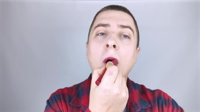 Close-up of a man painting his lips. The concept of protecting the rights of the LGBT community, a clear manifestation of homosexuality and the manifestation of female qualities in men.