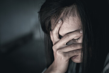 Scared young woman sitting in the corner of her bedroom, despair rape victim waiting for help,The concept of stopping violence against women and rape.