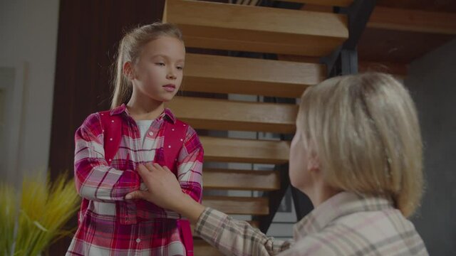 Portrait of irritated stubborn cute preadolescent schoolgirl with backpack standing with arms crossed, listening to mother's admonition and warning before school, looking frustrated and displeased.