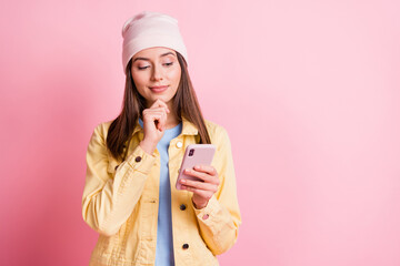 Photo of thoughtful happy brown haired girl hold look phone wear hat copyspace isolated on pink color background