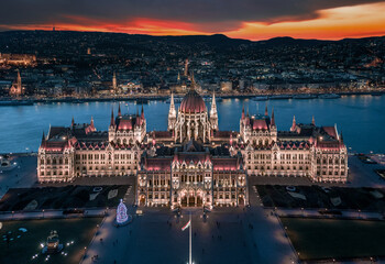 Budapest, Hungary - Aerial panoramic view of the beautiful illuminated Hungarian Parliament building at blue hour with Christmas tree. Buda Hills and River Danube at background on a December evening