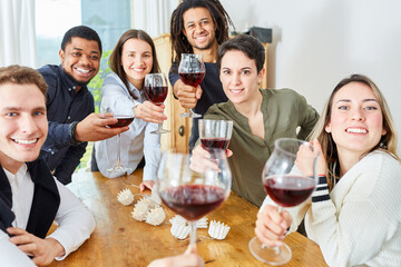 Glückliche Freunde zu Hause feiern mit einem Glas Rotwein