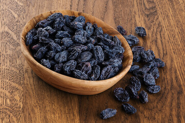 Black raisins on wooden background.