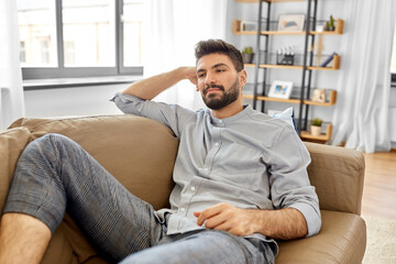 people and leisure concept - young man lying on sofa at home