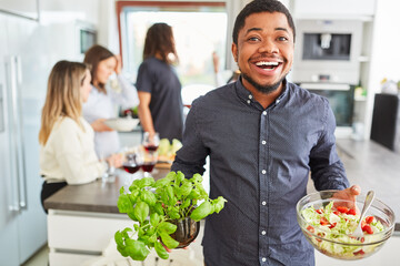 Mann mit Salat und Basilikum beim Vorbereiten für das Mittagessen