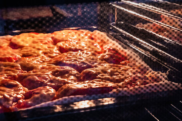 Food in a closed oven. Food with tomatoes and cheese baked in the oven